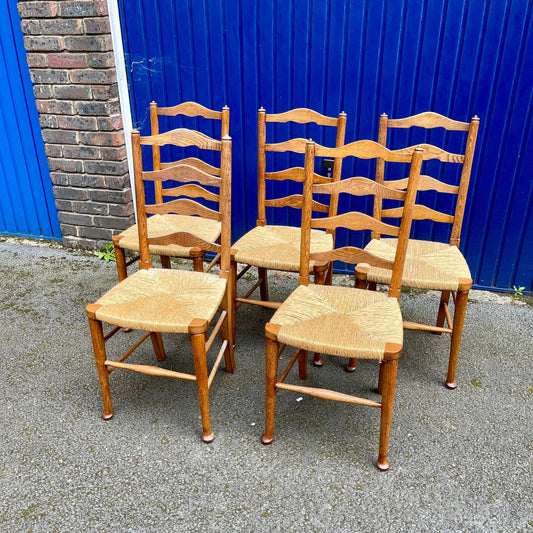 A Set Of Five Arts And Crafts Oak Rush-Seated Ladder Back Dining Chairs